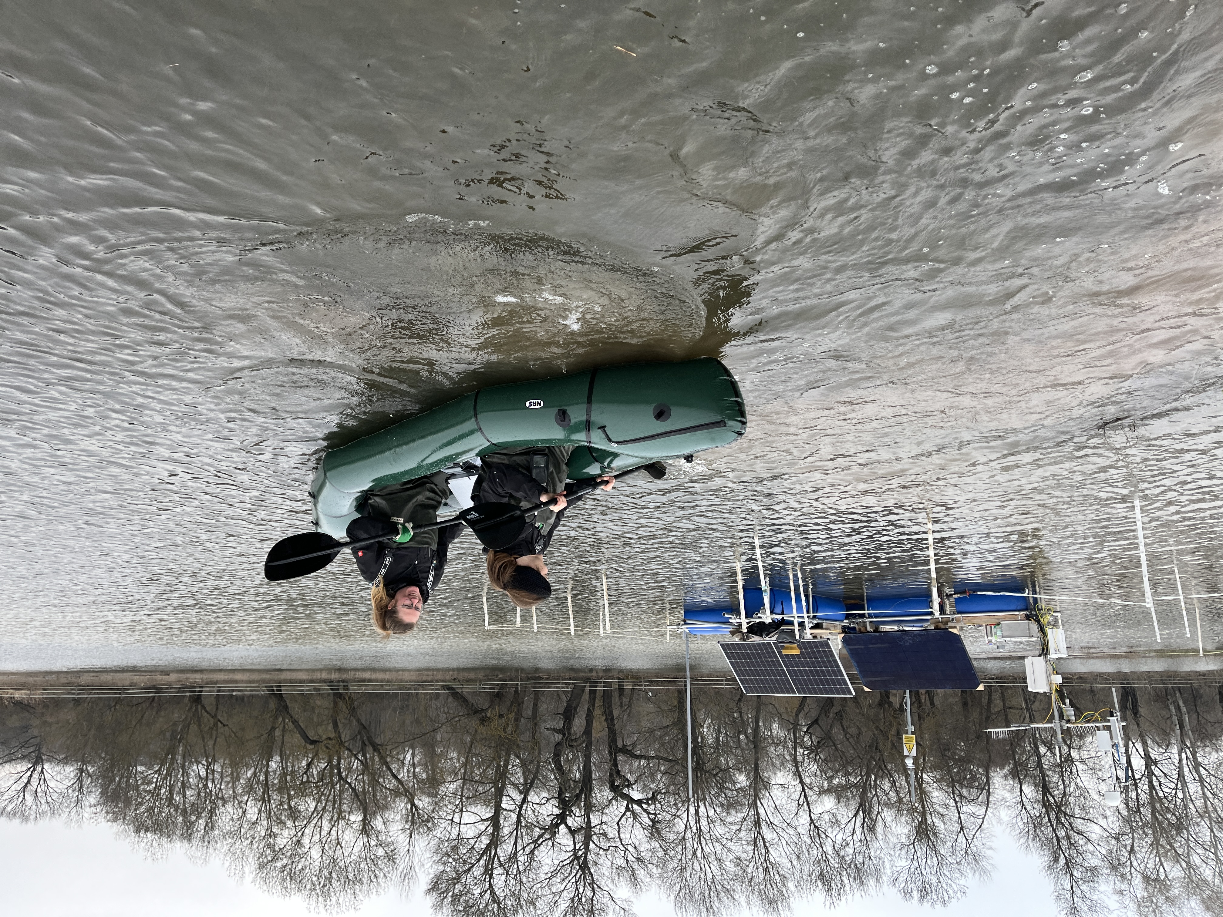 two women kayaking in the flooded field to check on the floating ec tower station